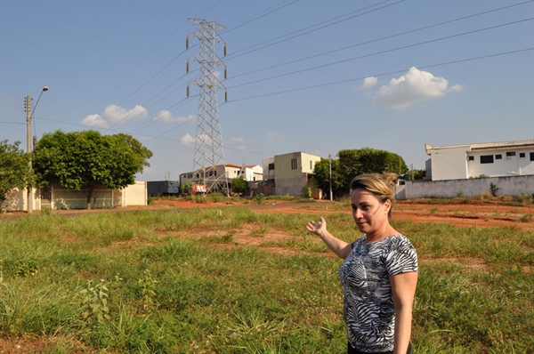 A cabeleireira Edna Diogo Oliveira aponta o mato alto nas obras