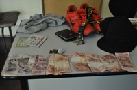 Dinheiro, porções de maconha e objetos pessoais apreendidos pela PM com os jovens
