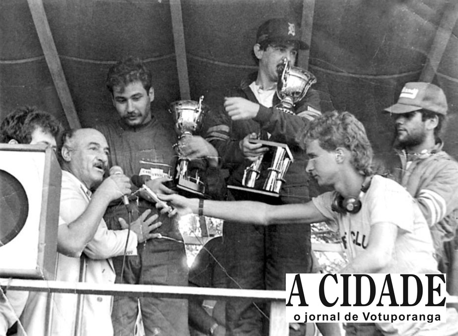 Em 1985, Votuporanga sediou a primeira e única corrida de Kart, que foi denominada “Felício Marão”. A prova foi realizada num circuito montado em volta da praça São Bento. A corrida deu-se no dia 20 de outubro, e teve como principal organizador o saudoso Pedrinho Marão. Na foto, conferindo a partir da esquerda: discursando, o então prefeito Mário Pozzobon, que entregava o troféu ao segundo colocado na prova, o piloto Zancaner, que disputou a segunda bateria. Na frente, entre outros, o radialista Rogério de Assis