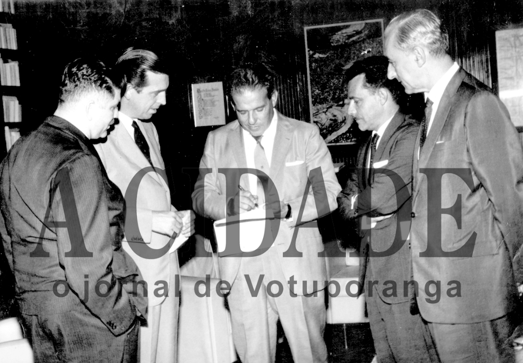 Votuporanga foi a primeira cidade do Brasil a reivindicar uma Usina de Álcool e Açúcar. Esta foto é do dia 12 de fevereiro de 1964. Poucos dias depois estourou a “Revolução de Março de 1964”que implantou a Ditadura Militar. Em Brasília,  Dalvo Guedes cumpria  o seu primeiro ato investido do cargo de prefeito e compareceu numa audiência com o presidente da República . É que o Presidente havia lançado um projeto para incrementar a implantação de Usinas de Alcool e Açucar no Brasil. Votuporanga foi a primeira a se habilitar para uma concessão. O despacho presidencial foi de imediato como mostra a foto, o presidente assinando o documento. Só que a obra não saiu do papel porque veio o Regime Militar e os atos de João Goulart tornaram-se nulos. Este é  o momento histórico do despacho presidencial. Ao lado de Dalvo Guedes aparece o deputado  Rubens Paiva (morto na ditadura). Na direita o saudoso jornalista Nélson Camargo e o saudoso prefeito Hernani de Matos Nabuco. Dalvo Guedes, numa entrevista,  contou que a viagem à Brasília foi feito de fusca e com ele no volante. Outro detalhe: esta foto foi trancada a sete chaves durante todo o período de Regime Militar.

***Confira mais desta coluna em nossa edição impressa e online para assinantes.
