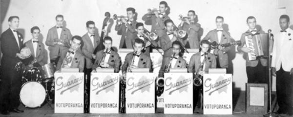 A orquestra Guarany - Os bailes dos anos 50 e começo de 60, foram abrilhantados ao som das grandes orquestras. Em Votuporanga, era destaque, a orquestra Guarany. Veja quem aparece na foto, da esquerda para a direita: Valdir Dezan, Alvim Algarve, Rubens Nogueira, Ivo Mataruco, Horácio dos Santos, Leonel Riva, Oldemar Furlaneto, Reynaldo Fernandes, Victor Mataruco, Leopoldo Grundi, Lourival Rocha, Eugênio da Silva (Tesourinha), Oliveira Messias Feliciano, Rómulo Riva, Amilar Riva, Alcebíades Ravazzi e Durvalino Setembrino. A foto é de autoria de Takeo Sato (Foto Votuporanga), datada em 31 de julho de 1959.