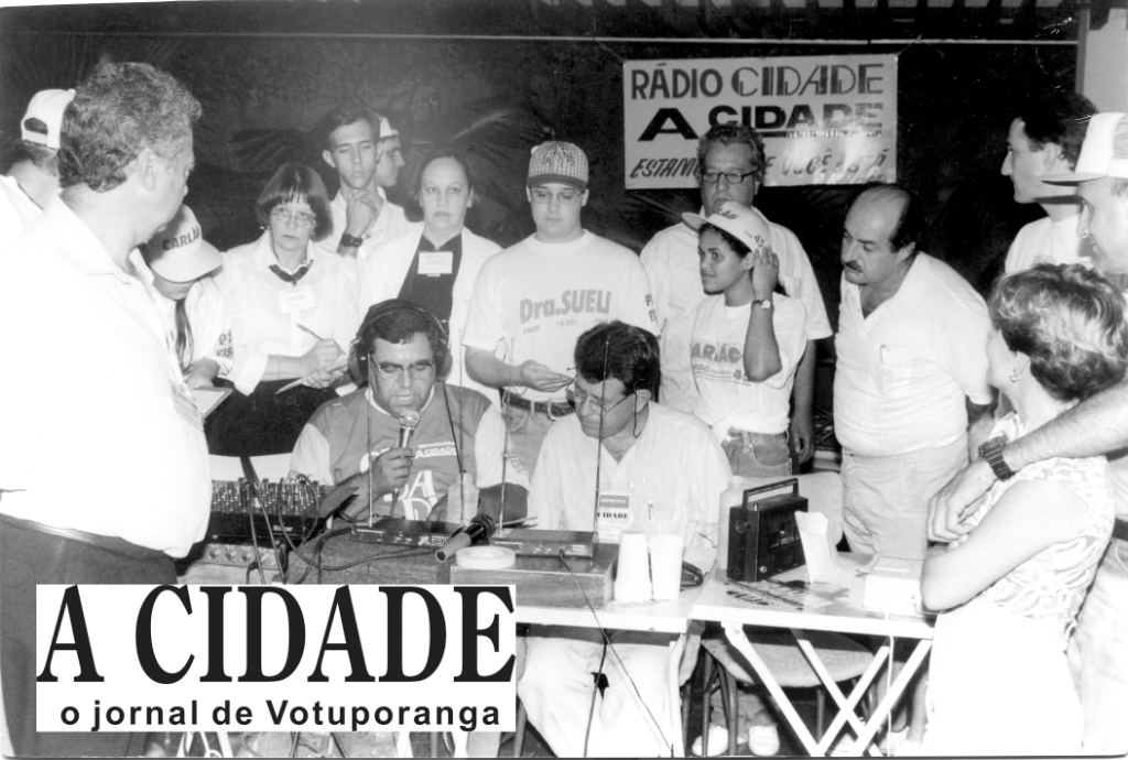 A mesa de transmissão da Rádio Cidade, nos anos 90, quando ainda não havia urna eletrônica e a apuração dos votos era feita urna por urna. Com o microfone, o radialista Léo Oliveira Filho e João Carlos Ferreira. Atrás deles, partidários acompanhavam o desempenho dos seus candidatos na urnas.