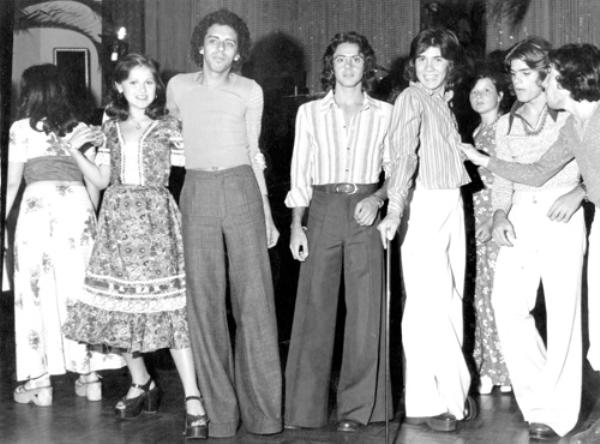 Baile do Hawaí - 1974 - O Votuporanga Clube estava decorado com muito verde e frutas tropicais. Era o tradicional Baile do Hawaí, realizado no dia 12 de setembro. Veja os detalhes: a moda era usar calça “boca de sino”. A partir da esquerda: Simone Calille, o saudoso Ney Vivo (histórico carnavalesco da cidade), Carlinhos De Haro, Abilinho Calille, Ana Maria Lacerda Soares (Pimpa), Caito e Júnior Santaella. A foto pertence ao álbum de família de Isis Portes Calille.