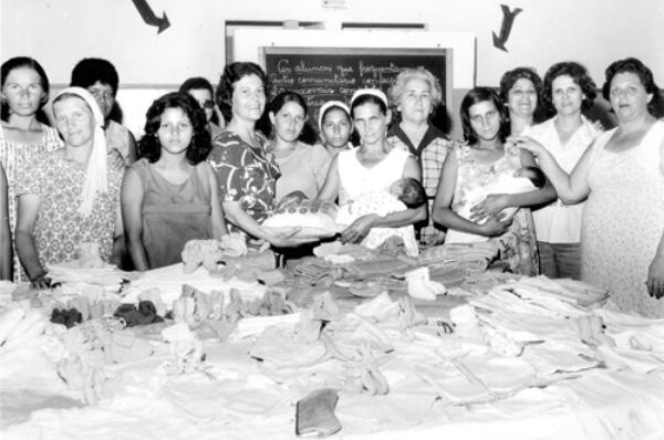 ENxovais para bebês - A Casa da Amizade do Rotary Club de Votuporanga sempre foi muito atuante, trabalhando em prol dos mais necessitados. Na foto de 1975, do arquivo de Walter Ferreira da Costa, registro da entrega de enxovais para as mães do Centro Comunitário do Bairro São João, pelas senhoras da Casa da Amizade, que era presidida por Shirley Mazaferro Costa (à frente com um enxoval na mão). Ainda aparecem a professora Maria Célia Marão Carvalho, a primeira-dama do município Neide De Haro, entre outras.