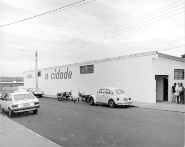 O prédio - O jornal A Cidade teve como sua primeira instalação o prédio da rua Ponta Porã, 818 (hoje sede do Cemad). Na parede, a primeira logomarca do jornal que estampou nossas primeiras edições que circularam em formato tablóide. Estacionados na frente os carros populares da época. 